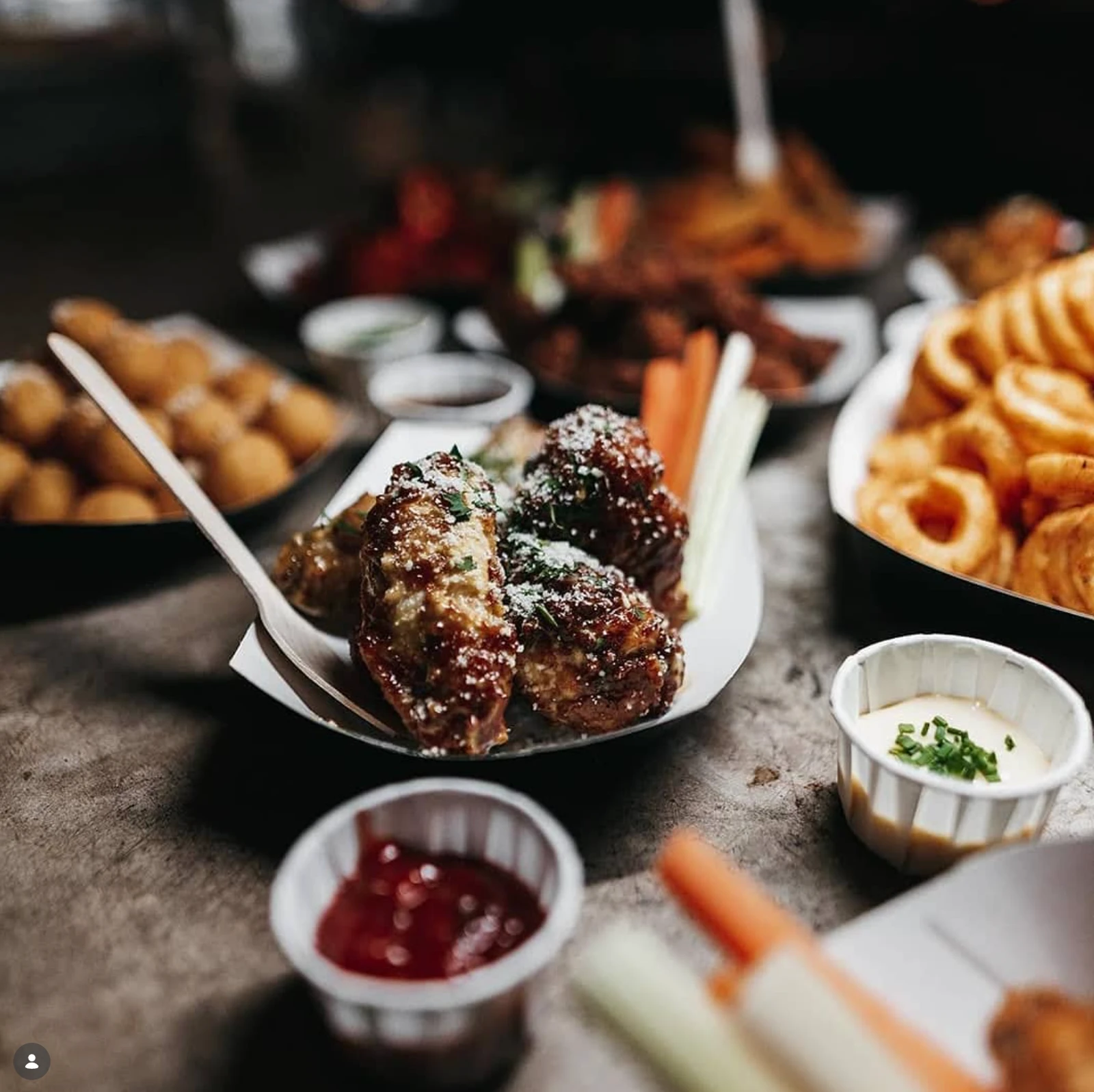 A bowl of loaded chicken with fries and dipping sauces